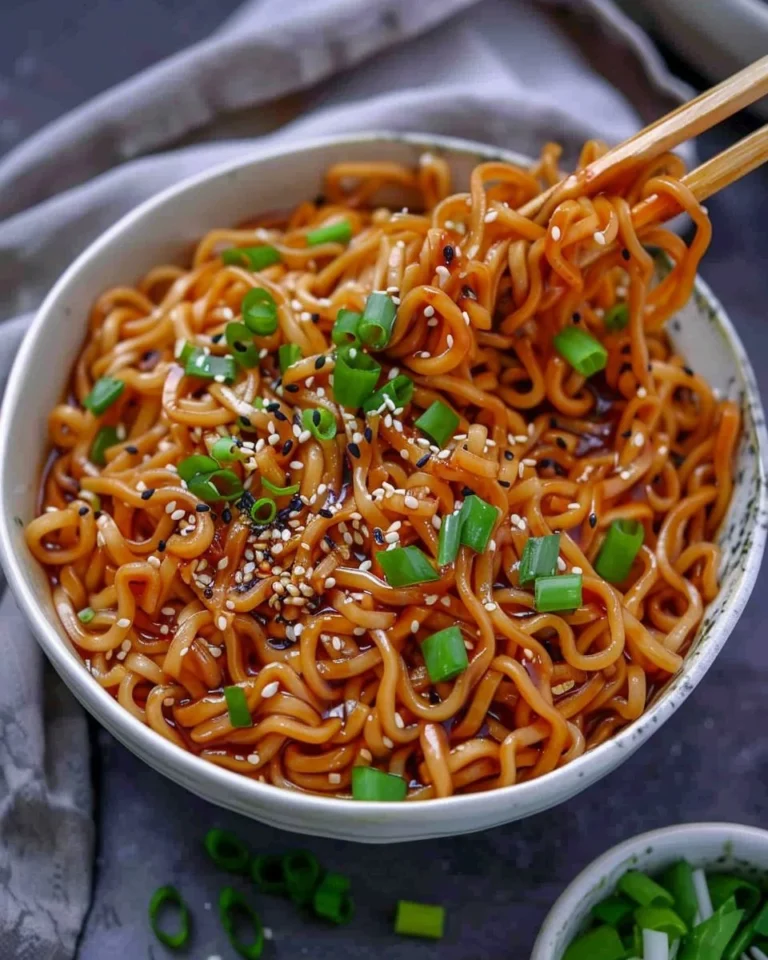 Bowl of saucy ramen noodles with toppings and chopsticks