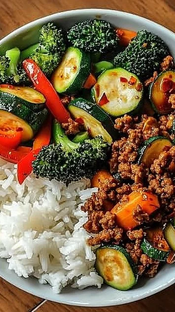 Spicy ground beef stir-fry bowl with garlic vegetables and steamed rice