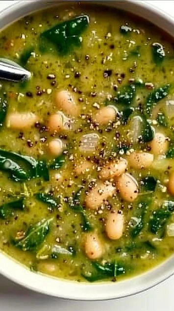 Bowl of homemade Spinach and White Bean Soup garnished with fresh herbs.