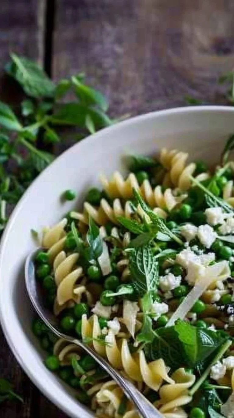 Plate of pea pasta with lemon, mint, and truffle oil garnished with fresh herbs